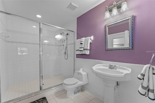 bathroom with tile patterned flooring, toilet, and a shower with shower door