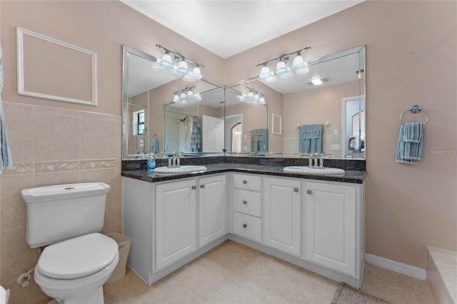 bathroom featuring tile patterned floors, vanity, toilet, and tile walls