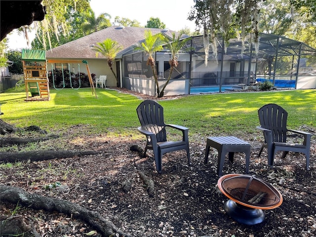 view of yard with a fire pit, a playground, and glass enclosure