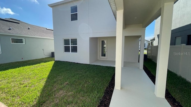 rear view of house featuring a patio, central AC, and a lawn