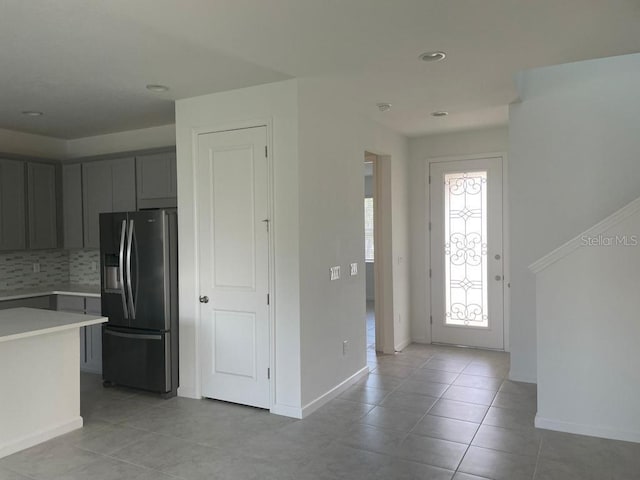 kitchen featuring stainless steel refrigerator with ice dispenser, gray cabinets, decorative backsplash, and light tile patterned floors