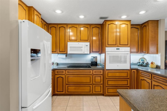 kitchen with tasteful backsplash, light tile patterned flooring, a textured ceiling, and white appliances