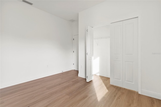 unfurnished bedroom with light wood-type flooring and a closet