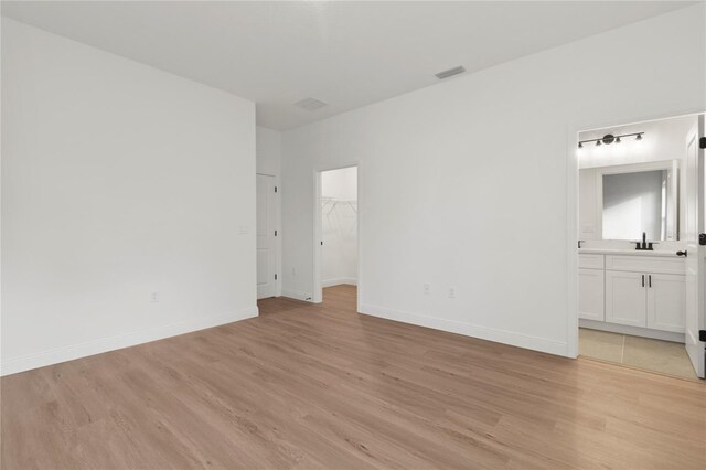 14735 SW 69th Court Rd, Ocala, FL 34473 - unfurnished bedroom featuring light wood finished floors, a sink, a spacious closet, and baseboards