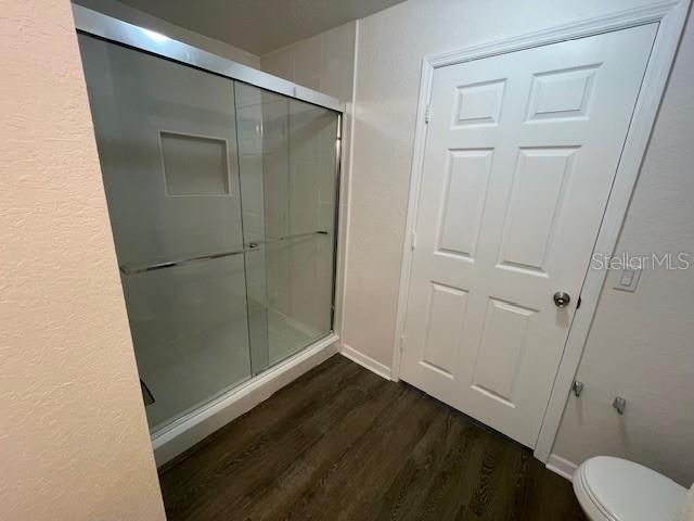 bathroom with an enclosed shower, hardwood / wood-style flooring, and toilet