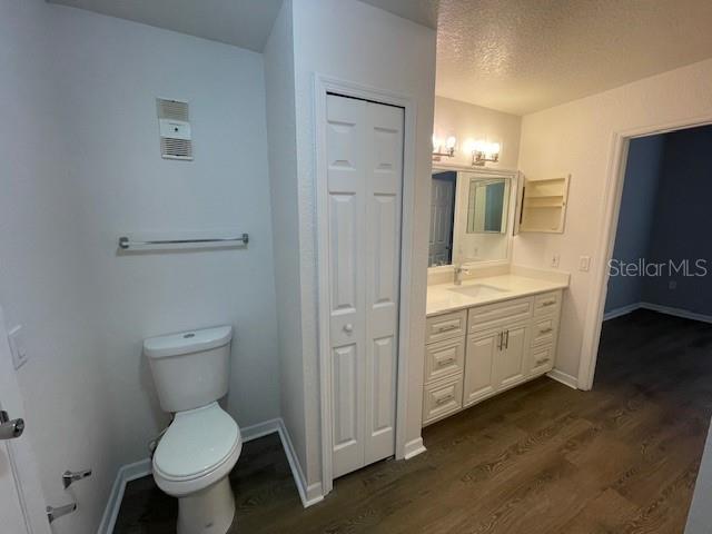 bathroom featuring vanity, hardwood / wood-style flooring, a textured ceiling, and toilet