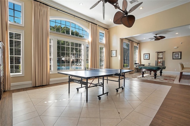 recreation room with a high ceiling, ornamental molding, light tile patterned flooring, and ceiling fan