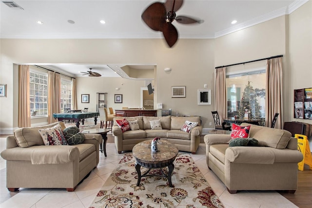 living room with a high ceiling, ornamental molding, light tile patterned flooring, and ceiling fan