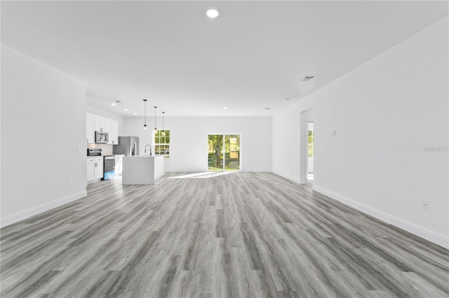 unfurnished living room featuring sink and light hardwood / wood-style floors