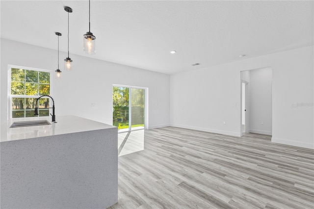 unfurnished living room featuring sink and light hardwood / wood-style flooring