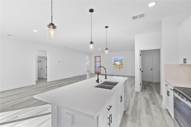 kitchen featuring pendant lighting, an island with sink, sink, white cabinets, and light hardwood / wood-style flooring