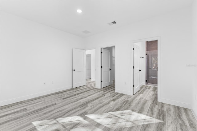 unfurnished bedroom featuring ensuite bathroom and light hardwood / wood-style floors