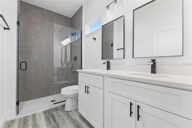 bathroom with vanity, toilet, an enclosed shower, and wood-type flooring