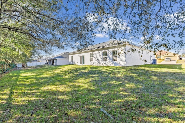 rear view of property with a lawn and central air condition unit