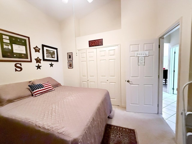 bedroom with high vaulted ceiling, light colored carpet, and a closet