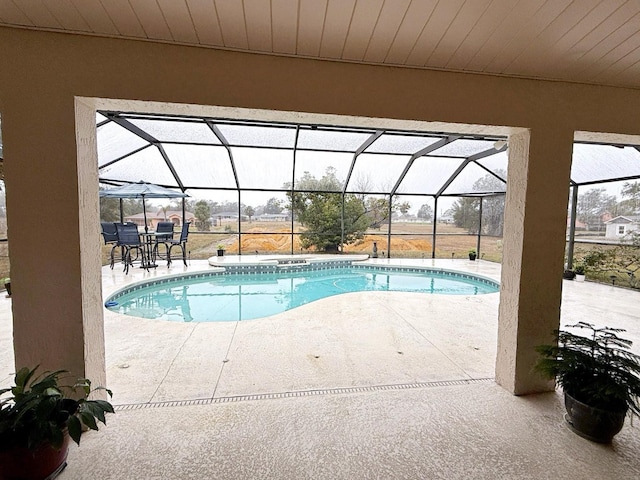 view of swimming pool featuring a patio area and glass enclosure