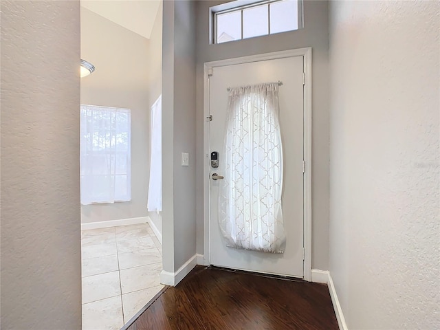 entryway with light hardwood / wood-style flooring, plenty of natural light, and a high ceiling