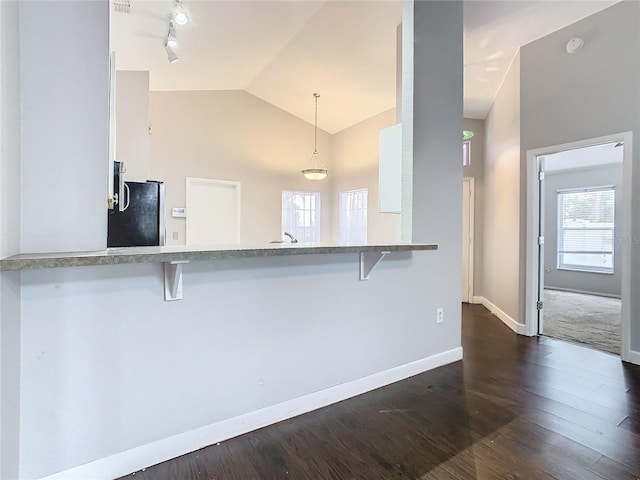 kitchen featuring stainless steel refrigerator, white cabinetry, hanging light fixtures, a kitchen breakfast bar, and kitchen peninsula