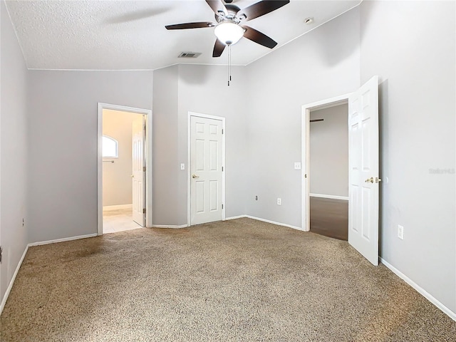 unfurnished bedroom featuring connected bathroom, high vaulted ceiling, light colored carpet, a textured ceiling, and ceiling fan