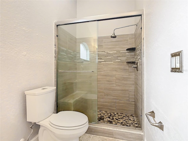 bathroom featuring tile patterned floors, toilet, and walk in shower