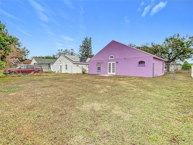 rear view of house featuring french doors and a lawn