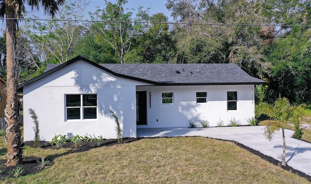 ranch-style home featuring stucco siding, roof with shingles, and a front yard