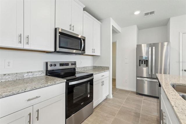 kitchen featuring light stone countertops, stainless steel appliances, white cabinets, and light tile patterned flooring