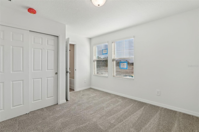 unfurnished bedroom featuring light carpet, a closet, and a textured ceiling