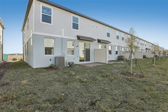 back of house featuring a lawn and central air condition unit