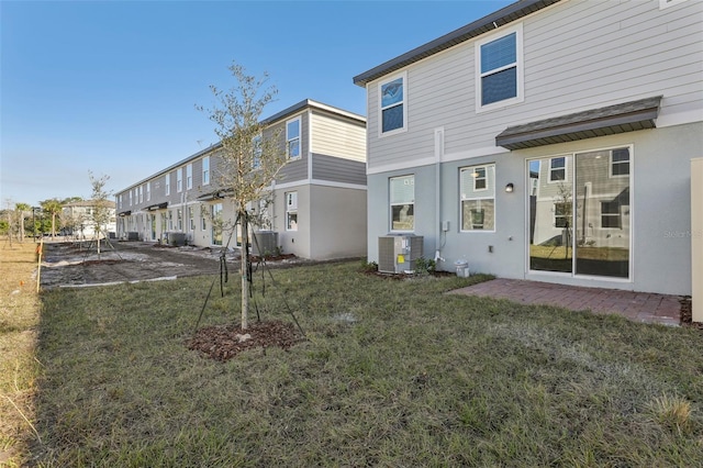 rear view of property featuring central AC unit and a lawn