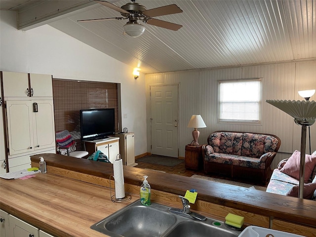 living room with ceiling fan, sink, and vaulted ceiling with beams