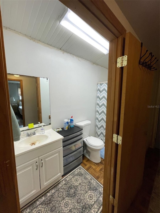 bathroom with vanity, parquet floors, walk in shower, and toilet