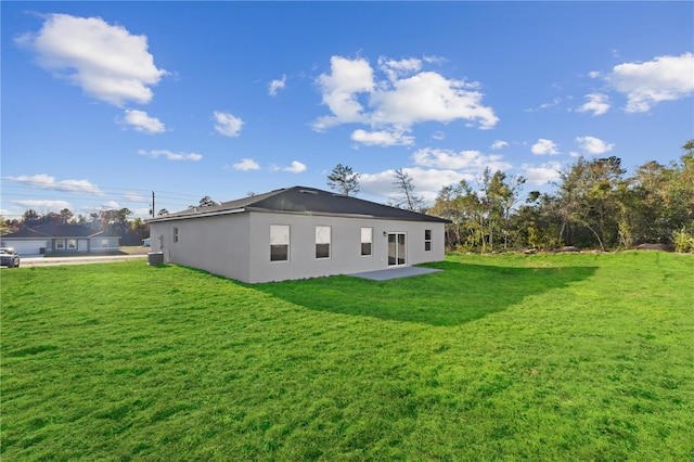 back of property with central AC unit and a yard