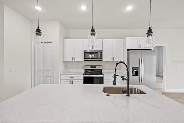 kitchen featuring pendant lighting, sink, white cabinetry, stainless steel appliances, and light stone countertops