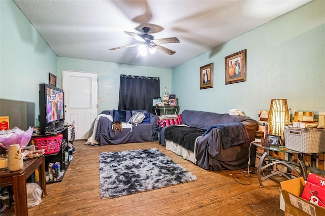 living room with hardwood / wood-style flooring, a textured ceiling, and ceiling fan