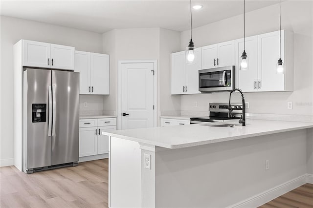 kitchen featuring white cabinetry, decorative light fixtures, stainless steel appliances, and kitchen peninsula