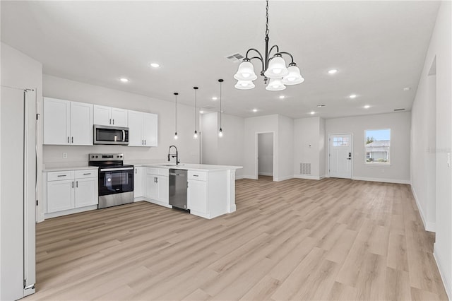 kitchen with sink, appliances with stainless steel finishes, an inviting chandelier, decorative light fixtures, and kitchen peninsula