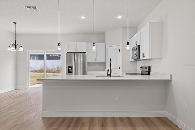 kitchen with pendant lighting, sink, an inviting chandelier, stainless steel appliances, and white cabinets