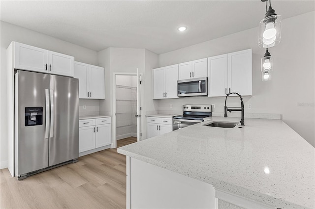 kitchen with stainless steel appliances, white cabinetry, pendant lighting, and kitchen peninsula