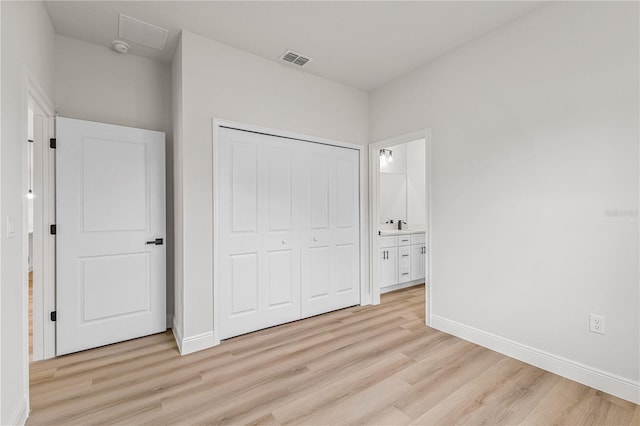 unfurnished bedroom featuring connected bathroom, light hardwood / wood-style floors, and a closet