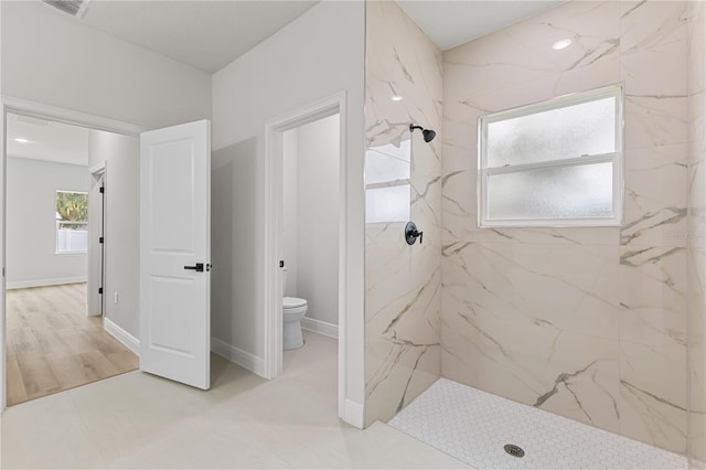 bathroom featuring a tile shower and toilet