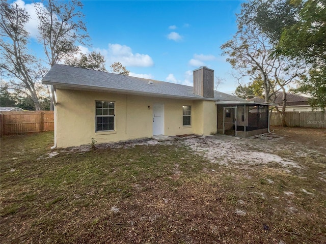 back of property featuring a yard and a sunroom