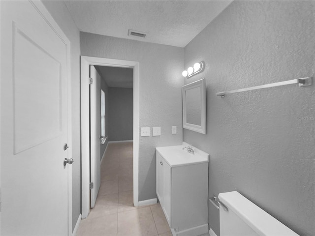 bathroom featuring tile patterned flooring, vanity, toilet, and a textured ceiling