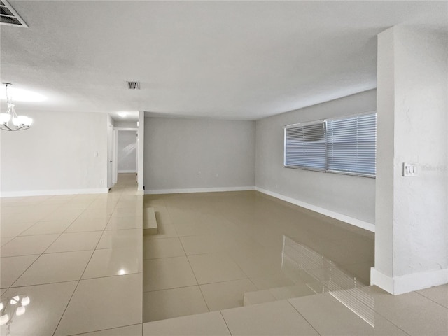 spare room featuring an inviting chandelier and tile patterned floors