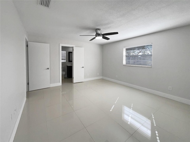 unfurnished bedroom featuring light tile patterned floors, a textured ceiling, and ceiling fan