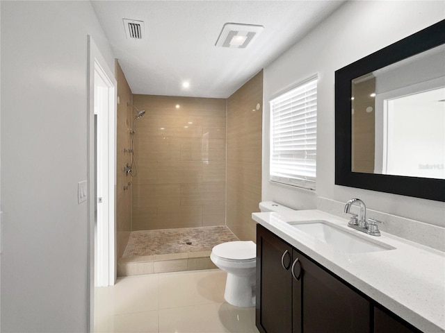 bathroom featuring tile patterned flooring, vanity, toilet, and a tile shower