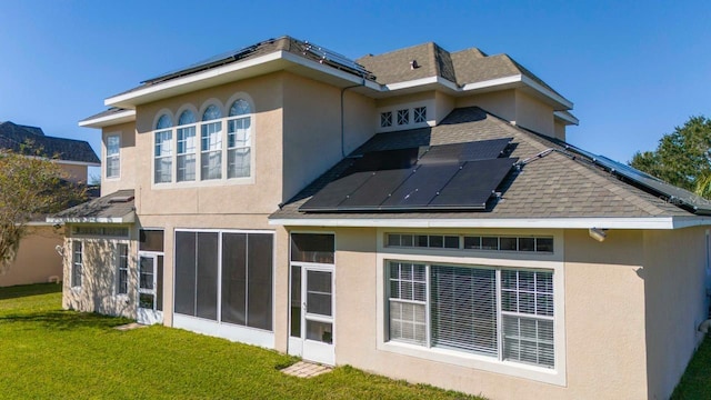 rear view of property featuring a yard and solar panels