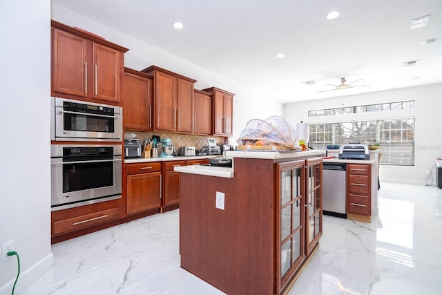 kitchen featuring a kitchen island, appliances with stainless steel finishes, backsplash, and ceiling fan