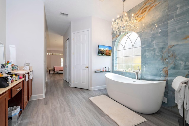 bathroom with hardwood / wood-style flooring, vanity, a bath, and an inviting chandelier