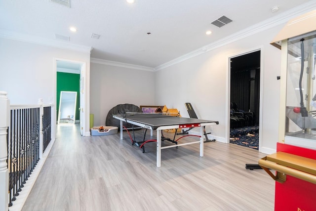 recreation room featuring crown molding, a textured ceiling, and light hardwood / wood-style floors